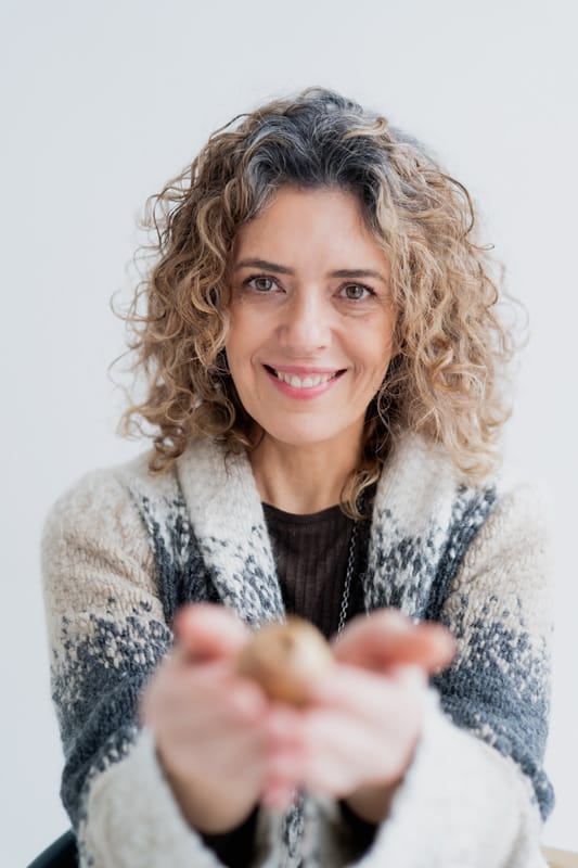 Malgorzata-sniezynska-psychoterapia-gestalt-lublin-mandragora-studio Usmiechnięta kobieta w jasnych kręconych włosach do ramion uśmiecha się. w dłoniach wyciągniętych do przodu trzyma ususzoną makówkę