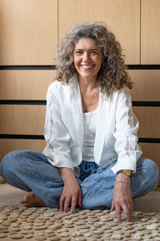 gosia-sniezynska-psycholog-lublin założycielka studia Mandragora siedzi bokiem na drewnianym krześle, spogląda w w twoją stronę i ciepło się uśmiecha